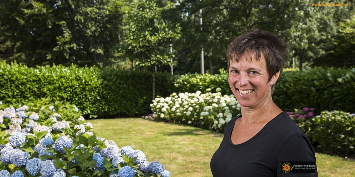 Anneke van Ginkel-Pol in een tuin met blauwe hortensia's